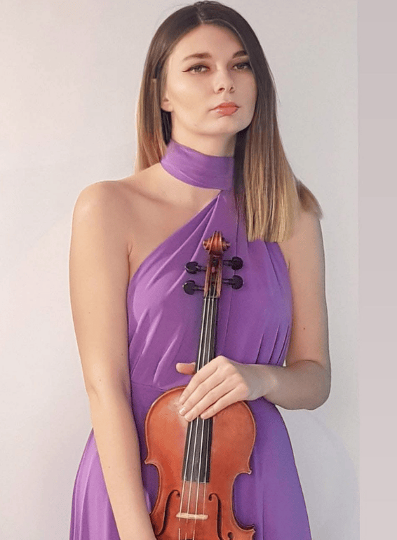 A young woman in a purple halter dress holding a violin against a white background.