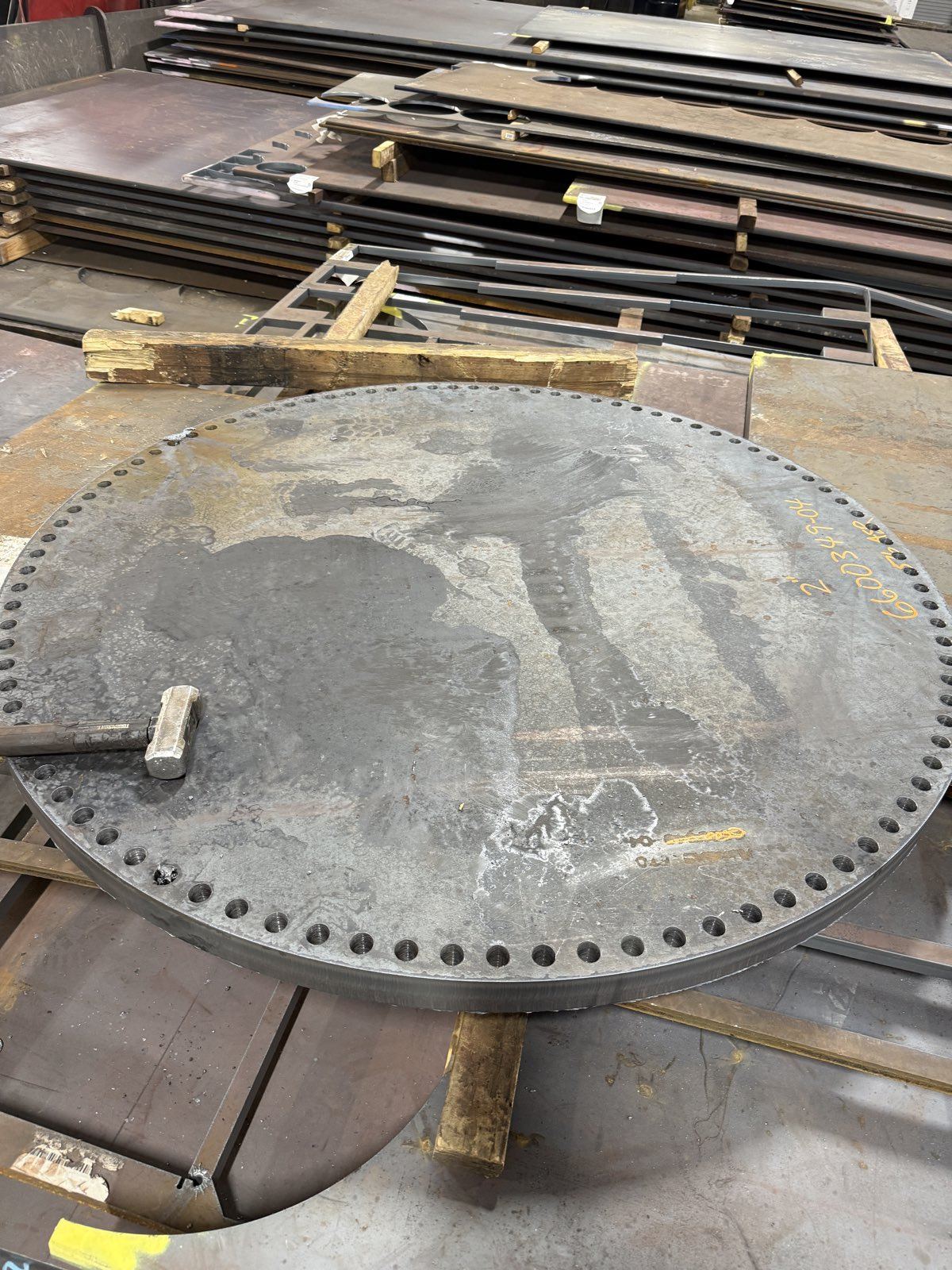 Heavy drilled circular plate resting on the shop floor