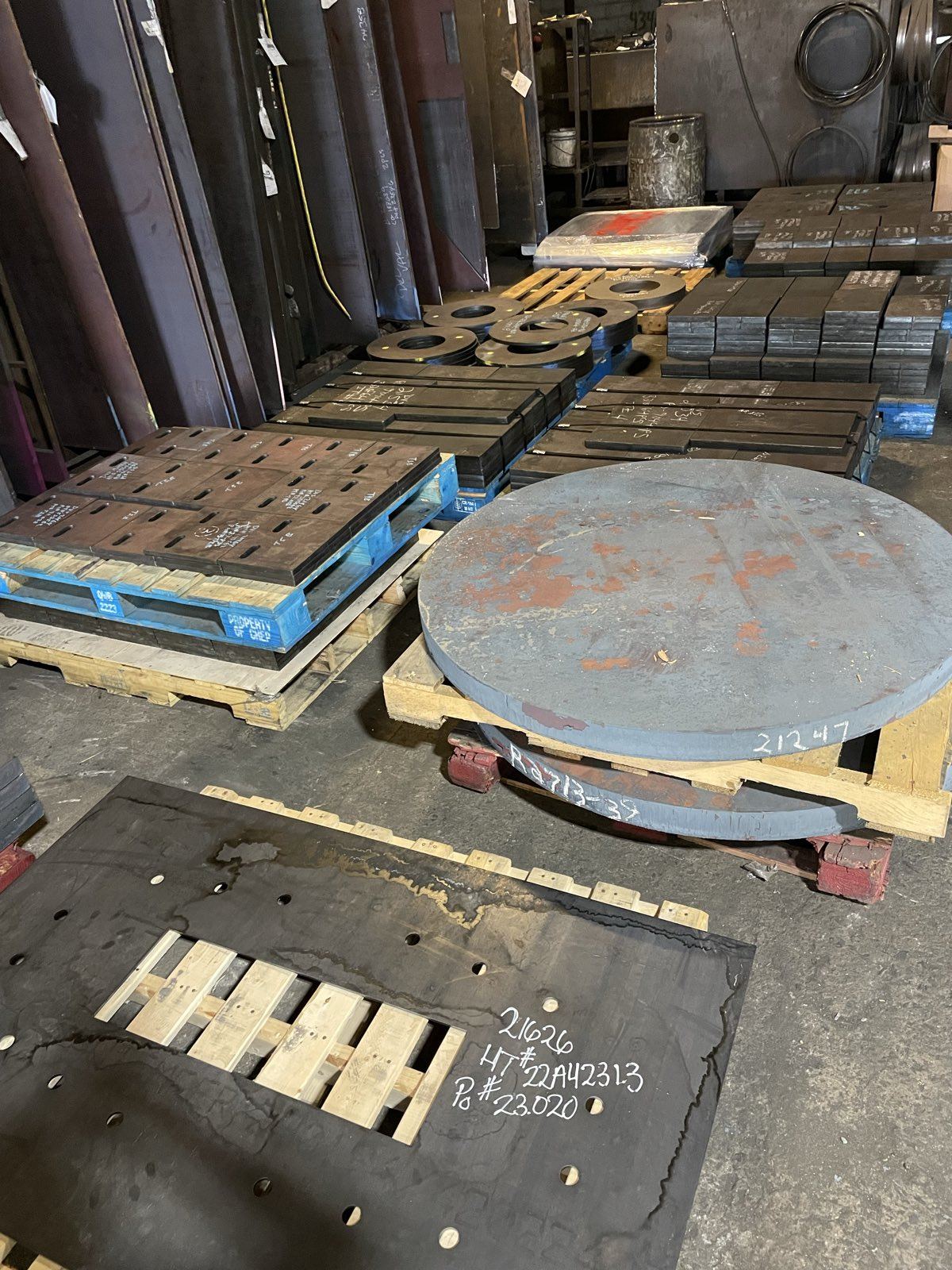Finished steel plate parts staged on pallets across the shop