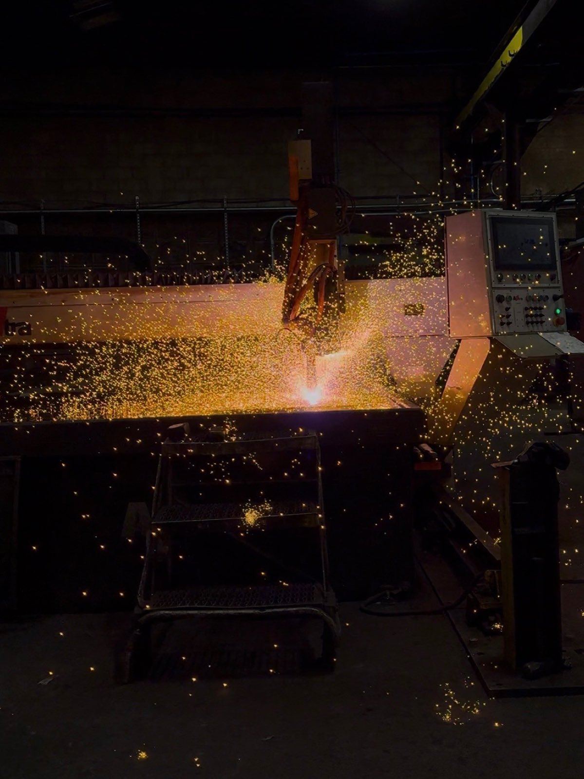 Sparks arc across the CNC plasma table during a cut