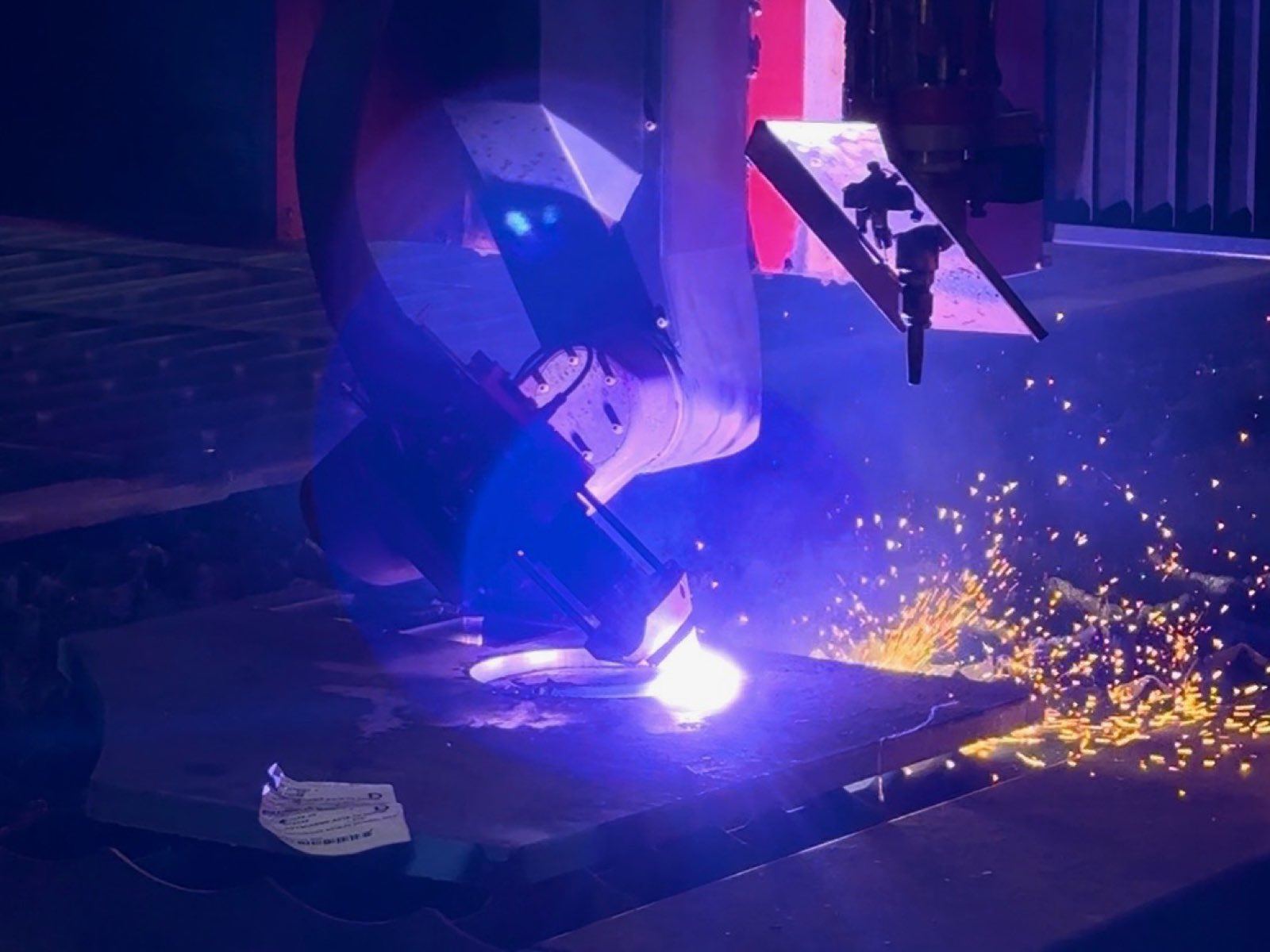 Plasma torch head cutting steel plate as sparks fly