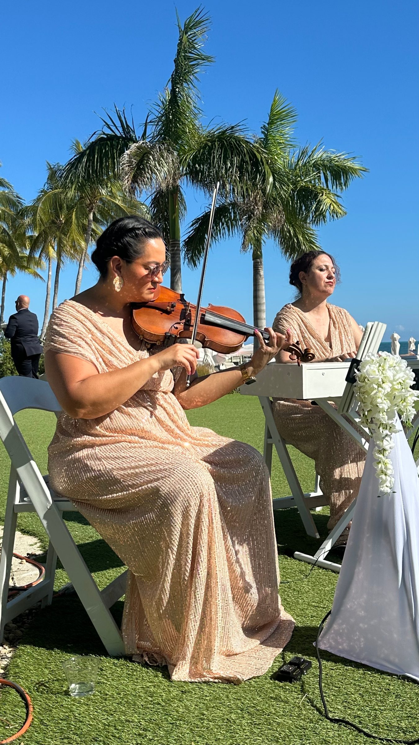 Violinist in West Palm Beach performing at a wedding, with the bride blurred out in the background and the scroll of the violin in silhouette